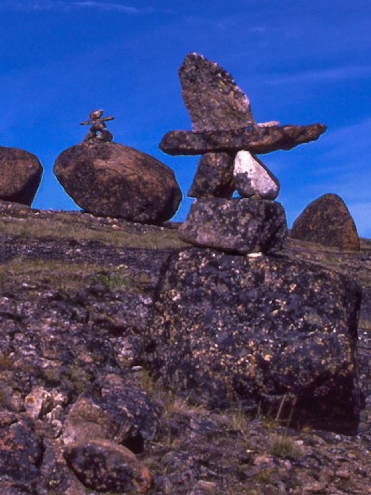 An inukshuk standing against a deep blue sky on the Akshayuk Pass, Auyuittuq National Park
